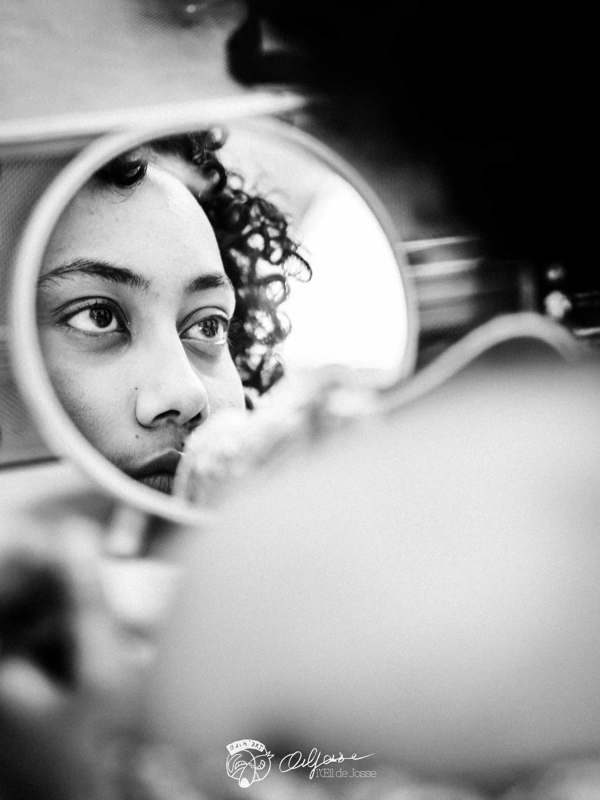 Le visage d’une comédienne se reflète dans un petit miroir de maquillage.